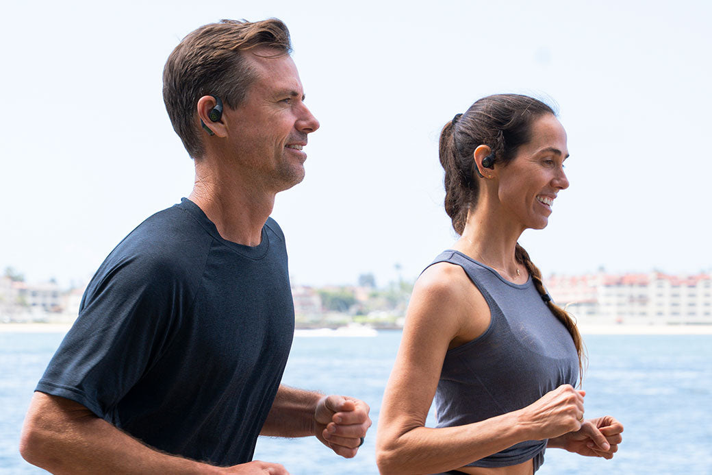 Man and women running while wearing epic open sport earbuds