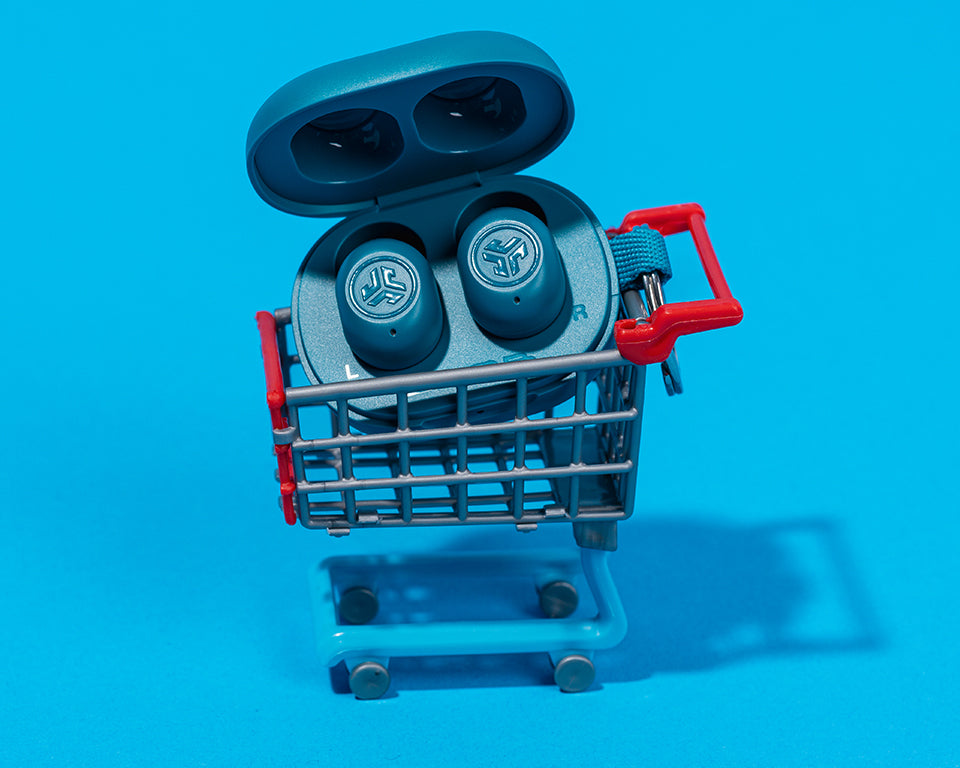 Jbuds mini in a miniature version of a shopping cart with a bright blue background