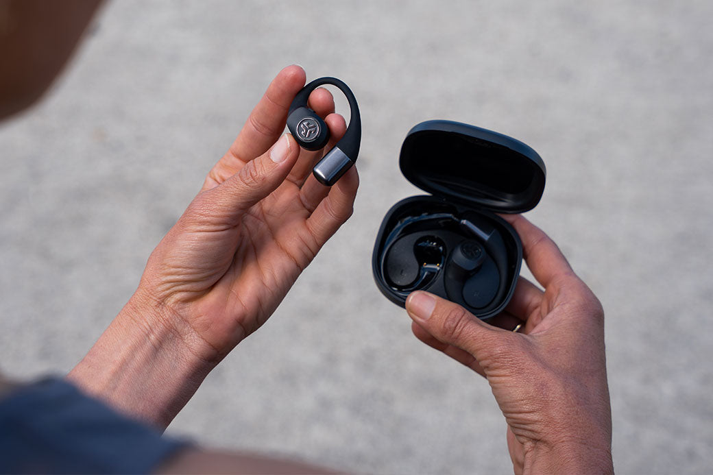 Close up of hands holding JLab Epic Open Sport earbud and case