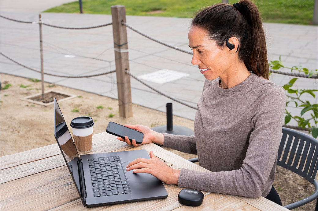 A woman connecting multiple devices to her JLab Epic Open Sport