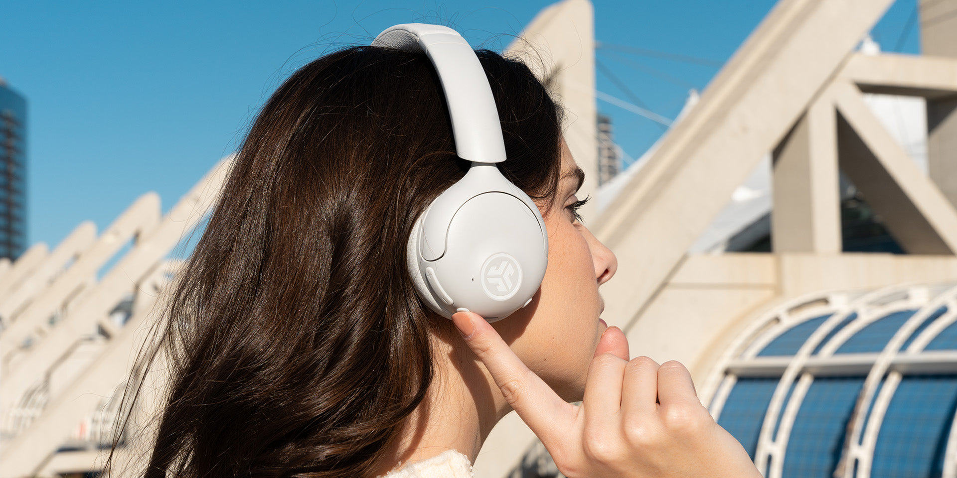 A woman enables noise canceling on her cloud white headphones.