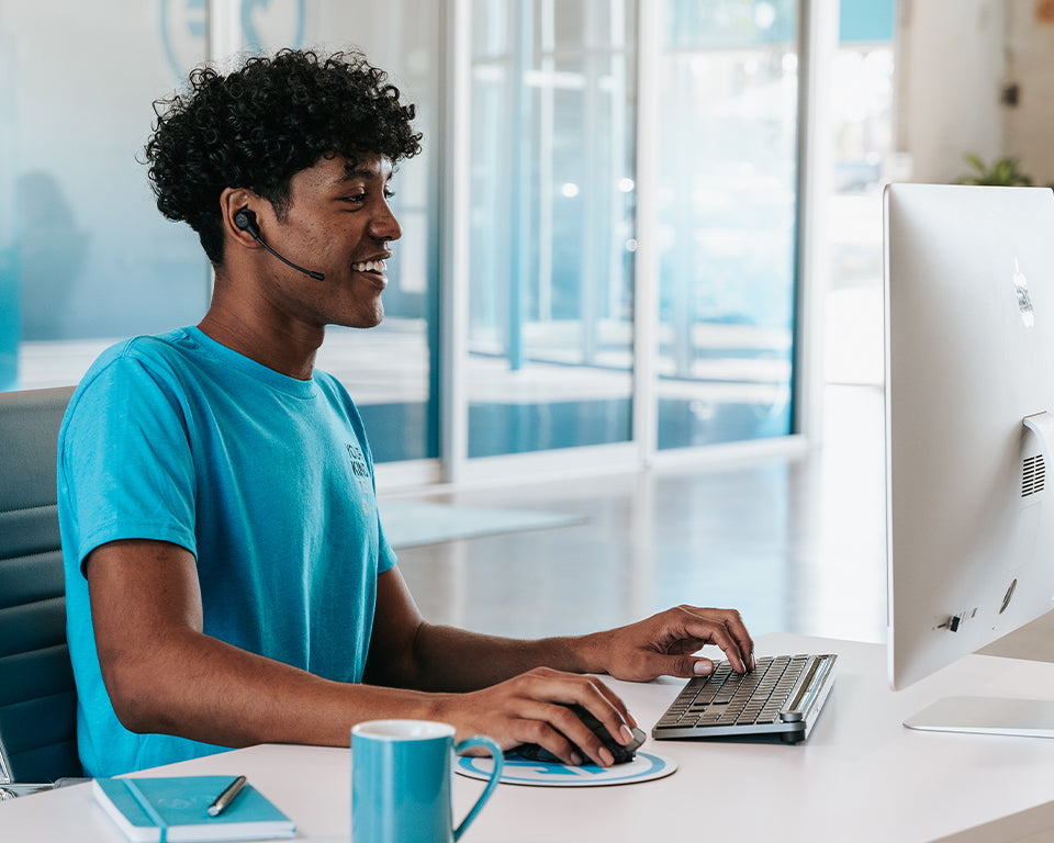 young man wearing jlab work buds while using his computer