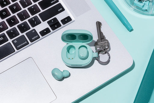 Close up of JBuds mini on a laptop with a light mint backdrop