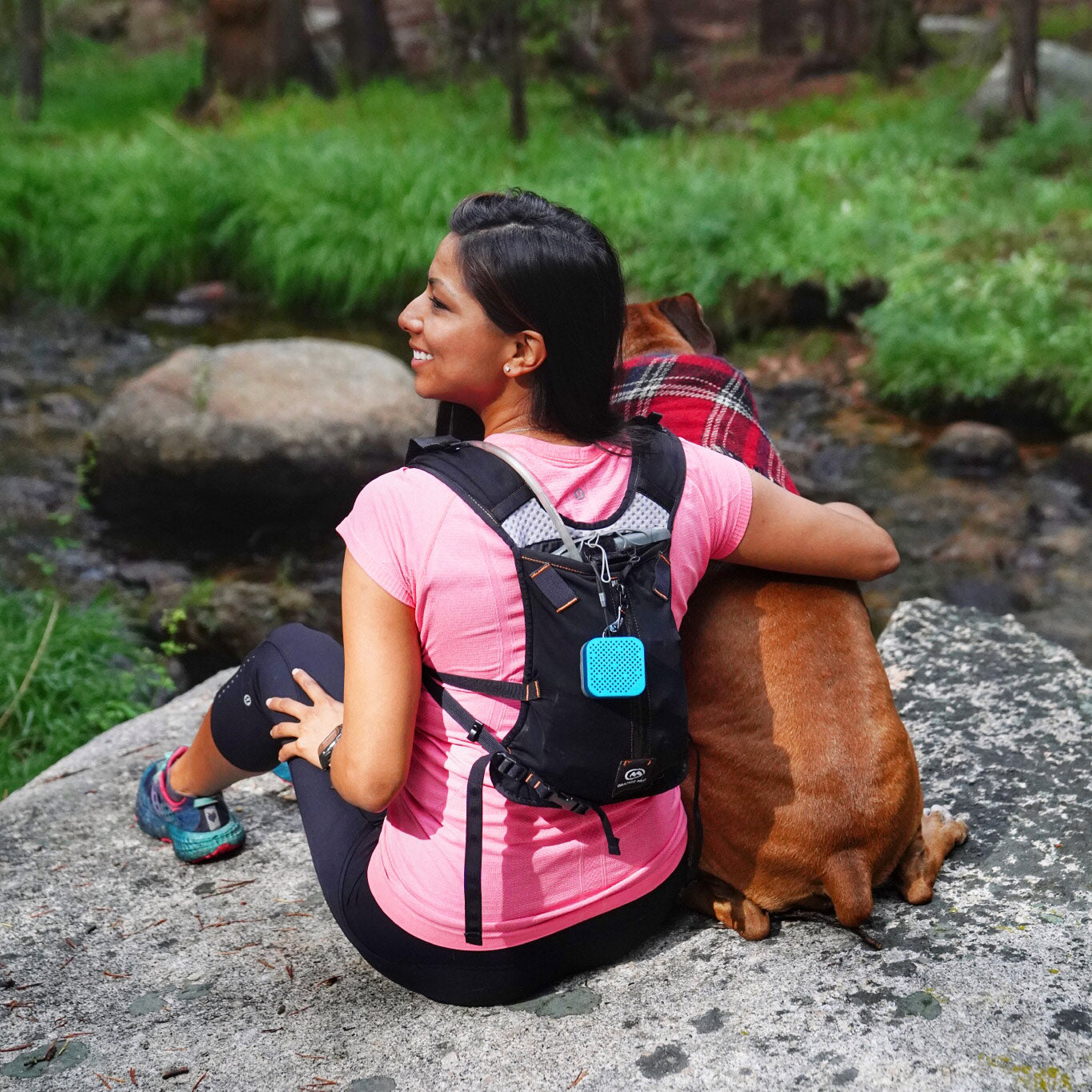 Woman Outdoors with Blue Crasher Micro Speaker Attached to Backpack